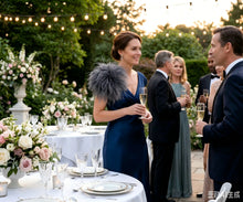 Load image into Gallery viewer, A guest wearing an elegant deep grey ostrich feather brooch lapel pin at a formal outdoor event.