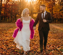 Load image into Gallery viewer, Hot pink ostrich feather shawl, lifestyle shot of the feather cape paired with a wedding dress for outdoor photos