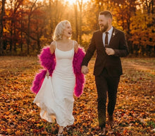 Load image into Gallery viewer, Hot pink ostrich feather shawl, lifestyle shot of the feather cape paired with a wedding dress for outdoor photos