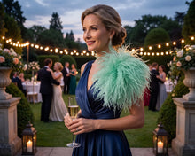 Load image into Gallery viewer, An elegant woman wearing a mint green ostrich feather brooch over a navy evening gown at an upscale dinner.