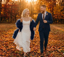 Load image into Gallery viewer, Navy blue ostrich feather shawl, lifestyle shot of the feather cape worn with a wedding dress in an autumn outdoor setting