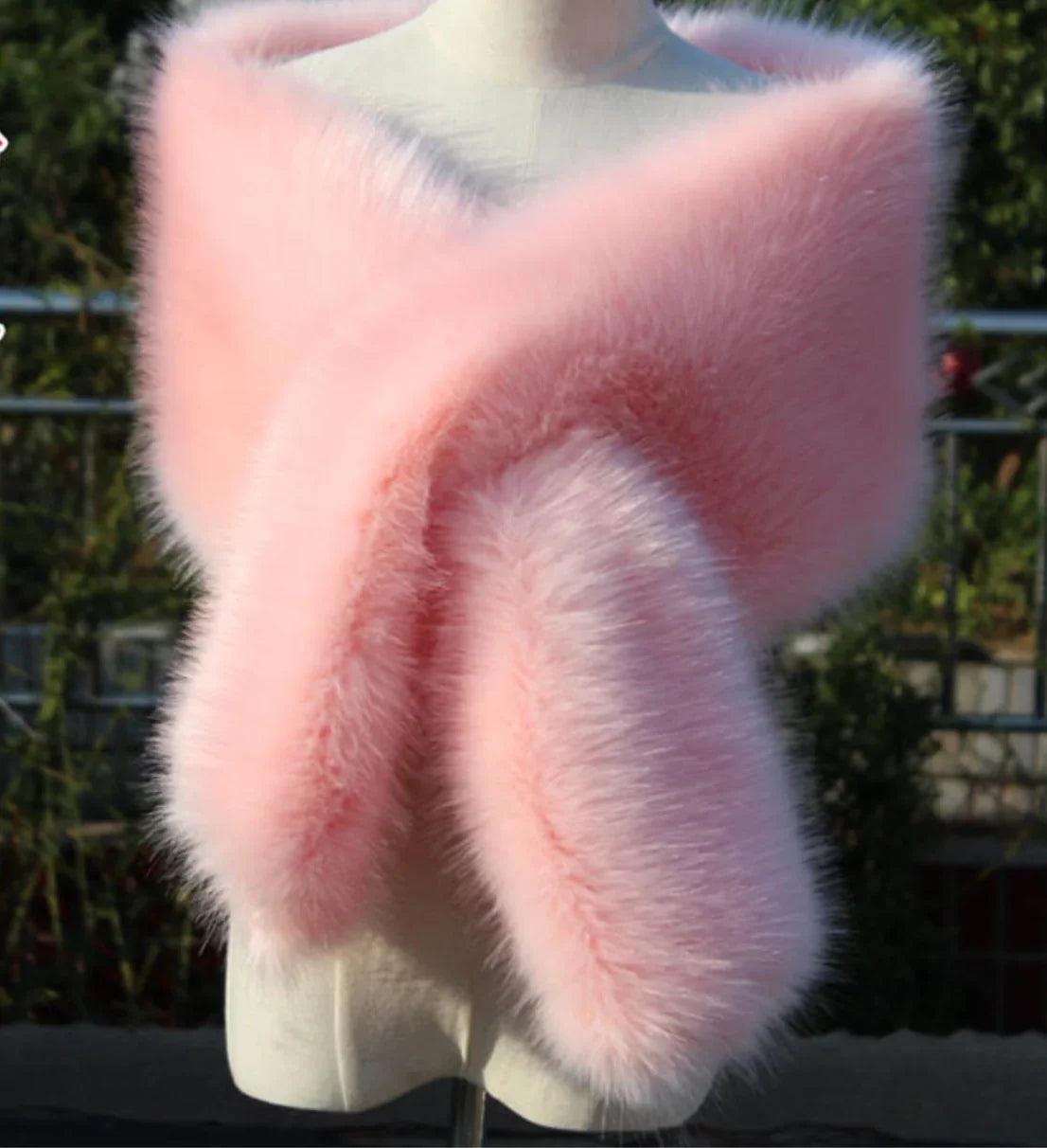 Pink fur stole on a mannequin against a blurred outdoor background
