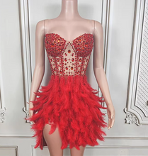 Load image into Gallery viewer, Red dress with feathered skirt on a mannequin against a white wall.