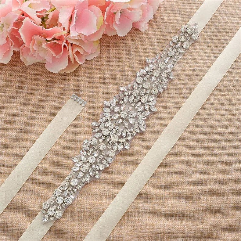 Detailed floral pattern rhinestone bridal belt with silver crystals, lying flat on a neutral background.