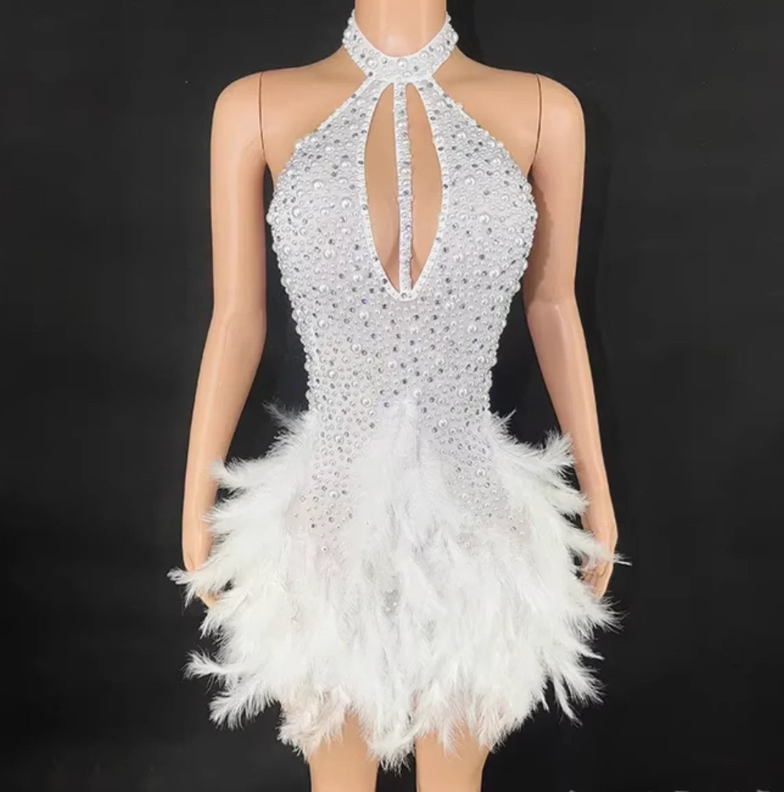 White beaded and feathered dress on a mannequin against a black background