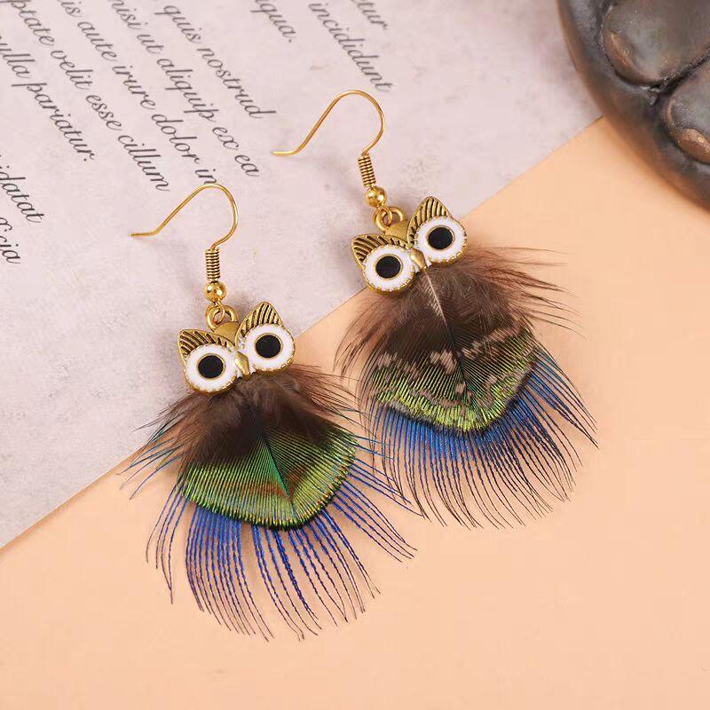 Pair of owl-shaped earrings featuring brown and blue peacock feathers.