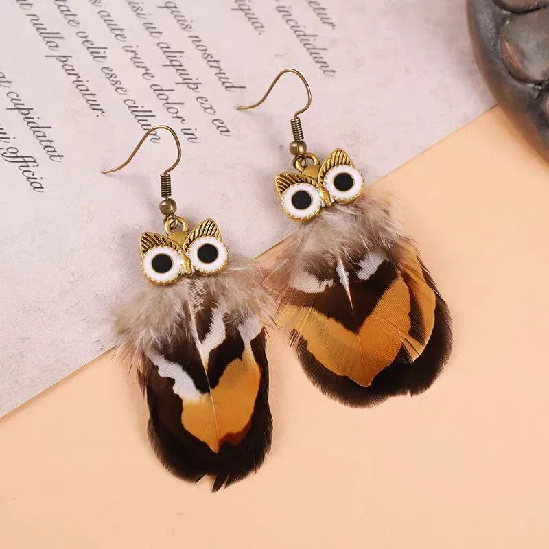 Pair of owl-shaped earrings featuring gold-tone metal owls and brown patterned feathers.