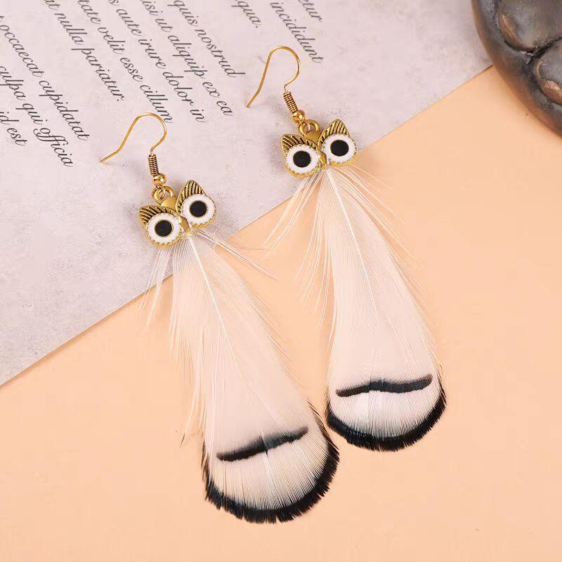 Pair of gold owl earrings with white and black tipped feathers