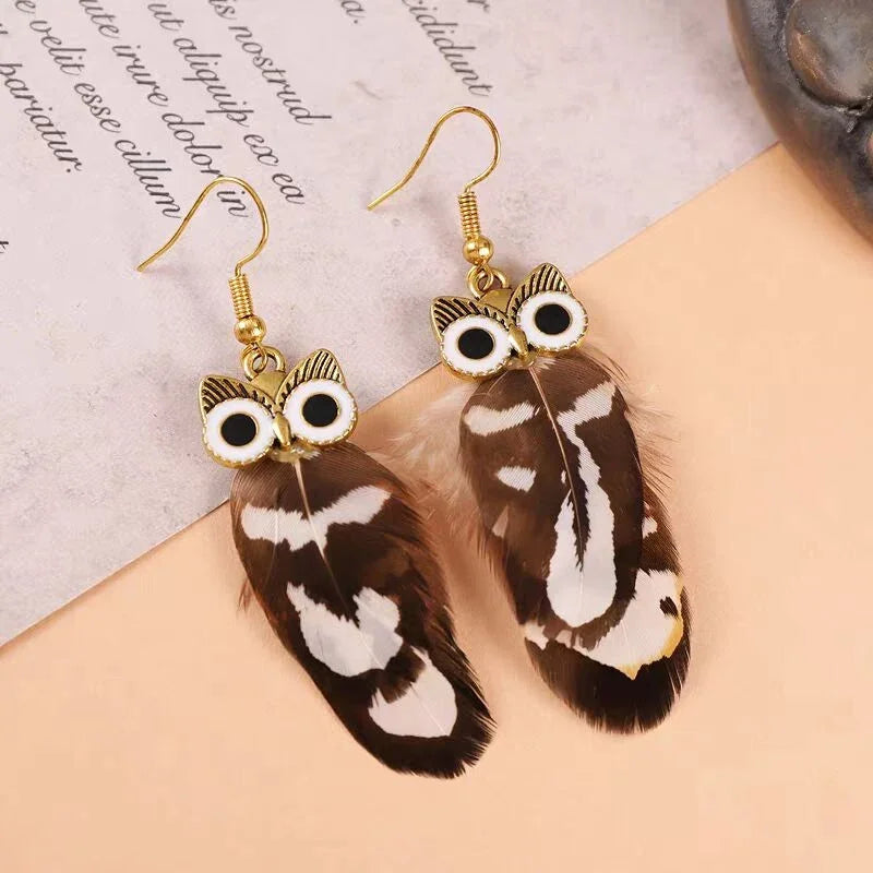 Gold-tone owl earrings with brown and white patterned natural feathers