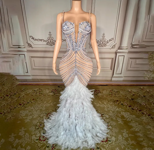 Elegant evening gown with feathered skirt on a mannequin against a decorative wall.