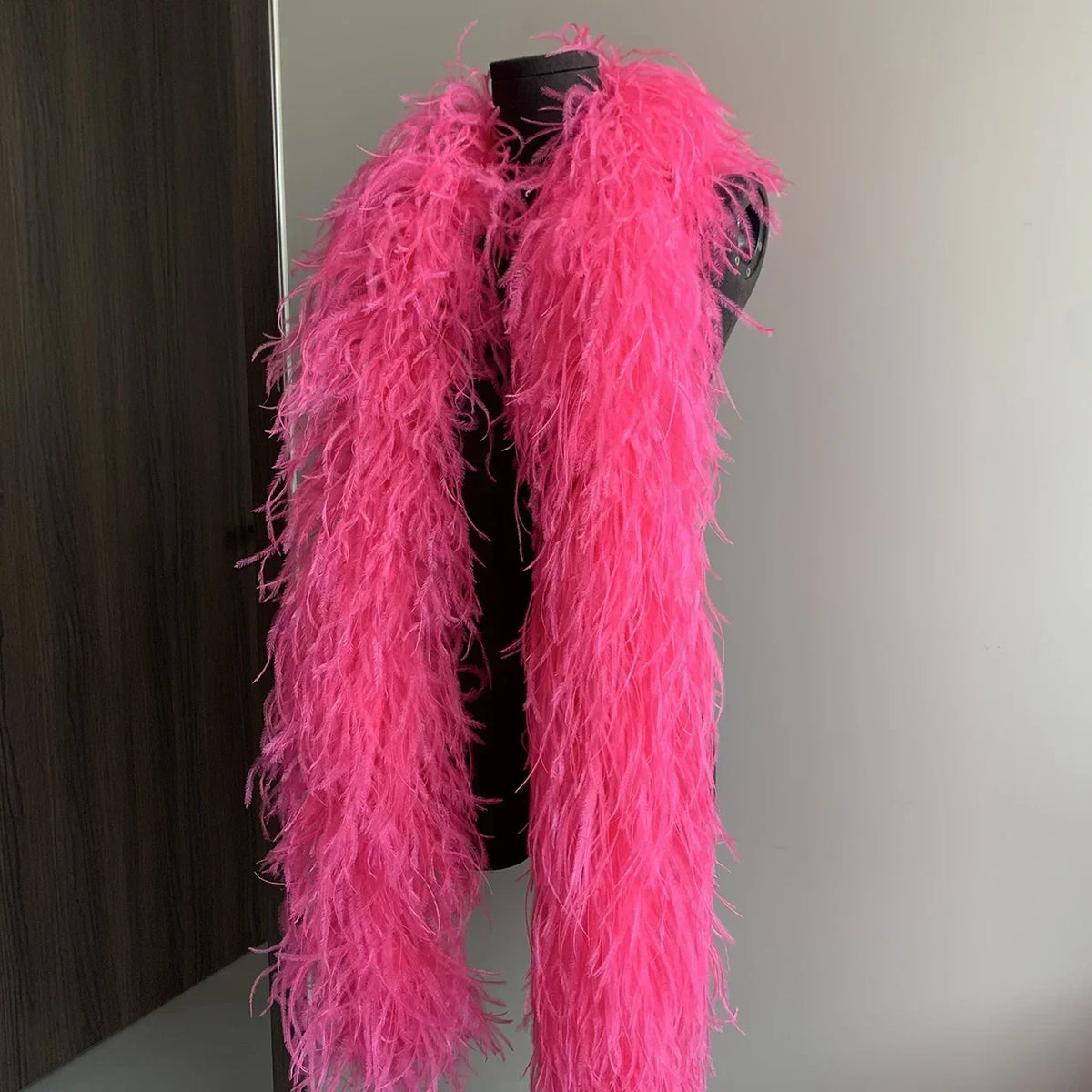Bright pink ostrich feather boa displayed on a black mannequin torso