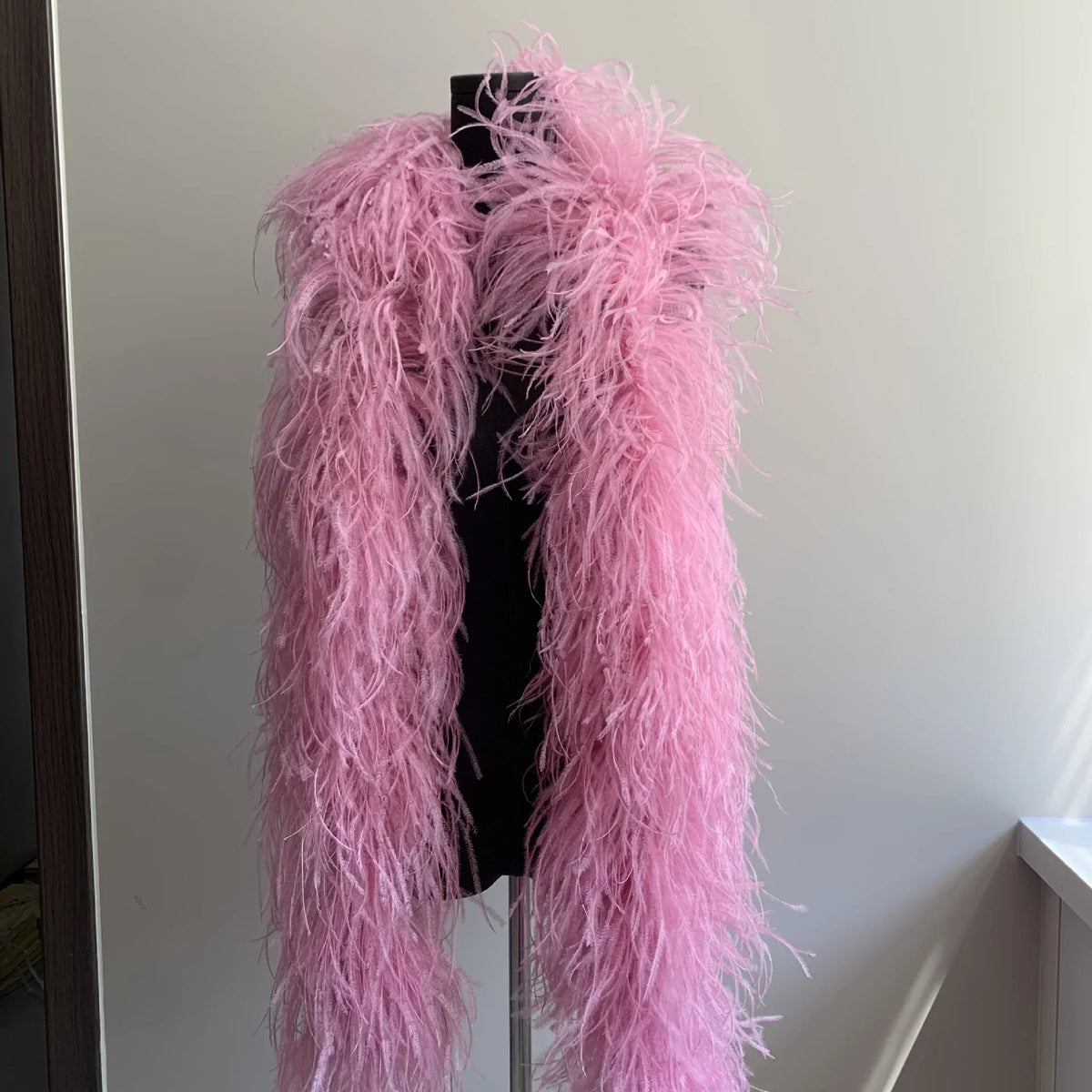 Pink ostrich feather boa displayed on a black mannequin torso