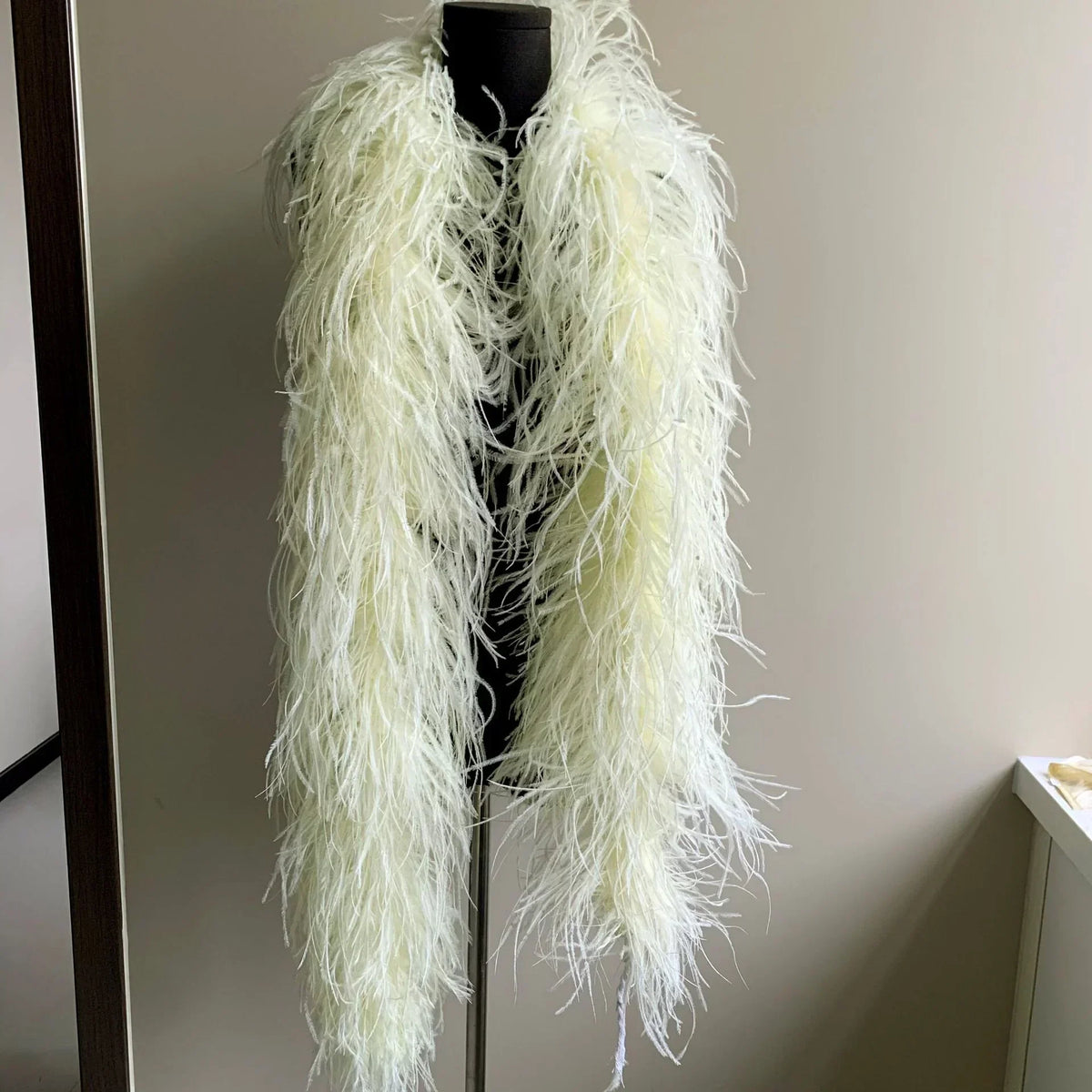 White ostrich feather boa displayed on a black mannequin torso