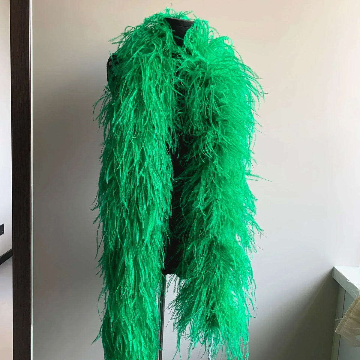 Bright green ostrich feather boa displayed on a black mannequin
