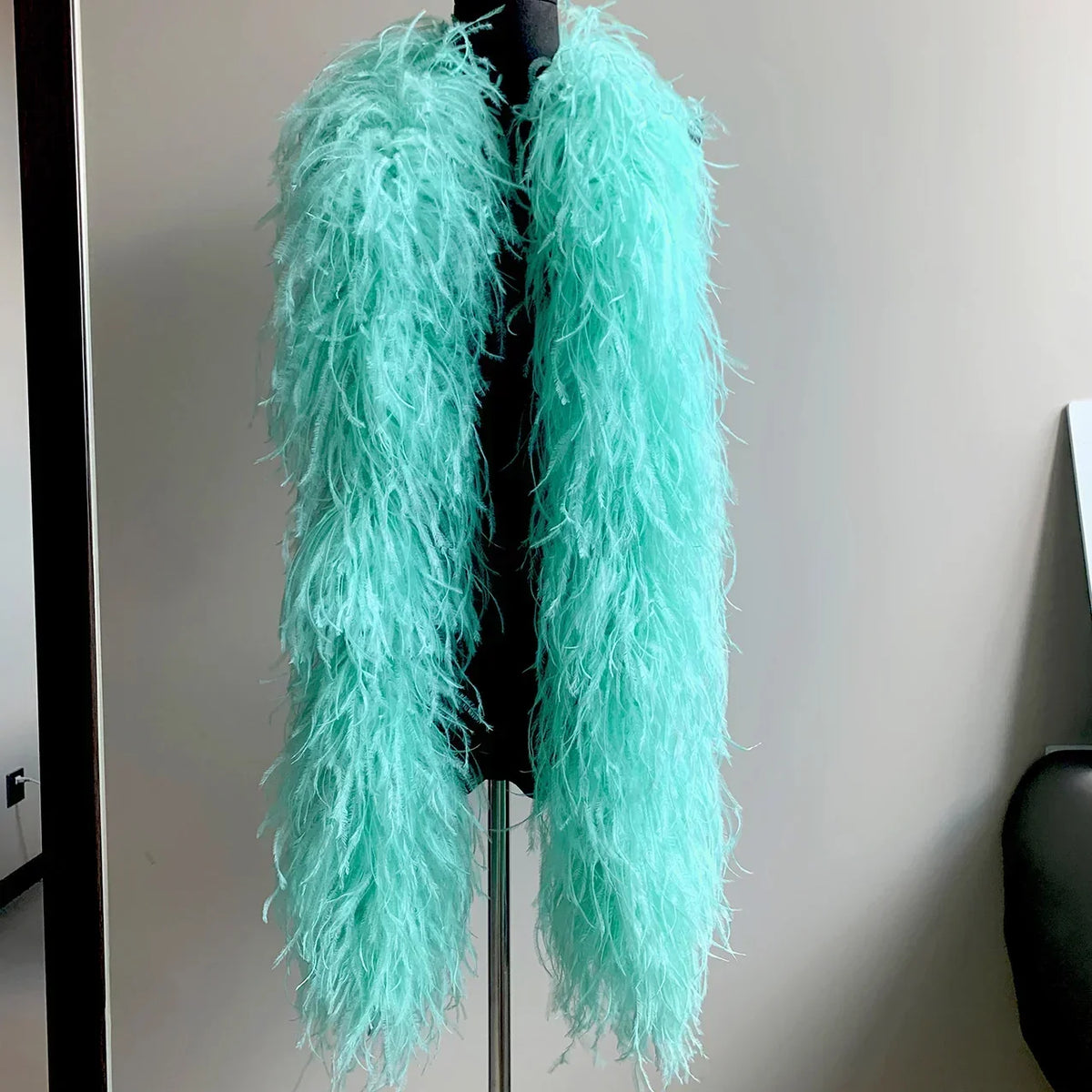 Mint green ostrich feather boa draped on a black mannequin