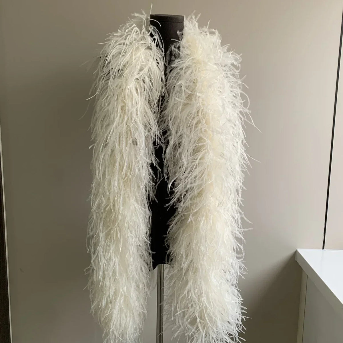 White ostrich feather wrap displayed on a black mannequin torso