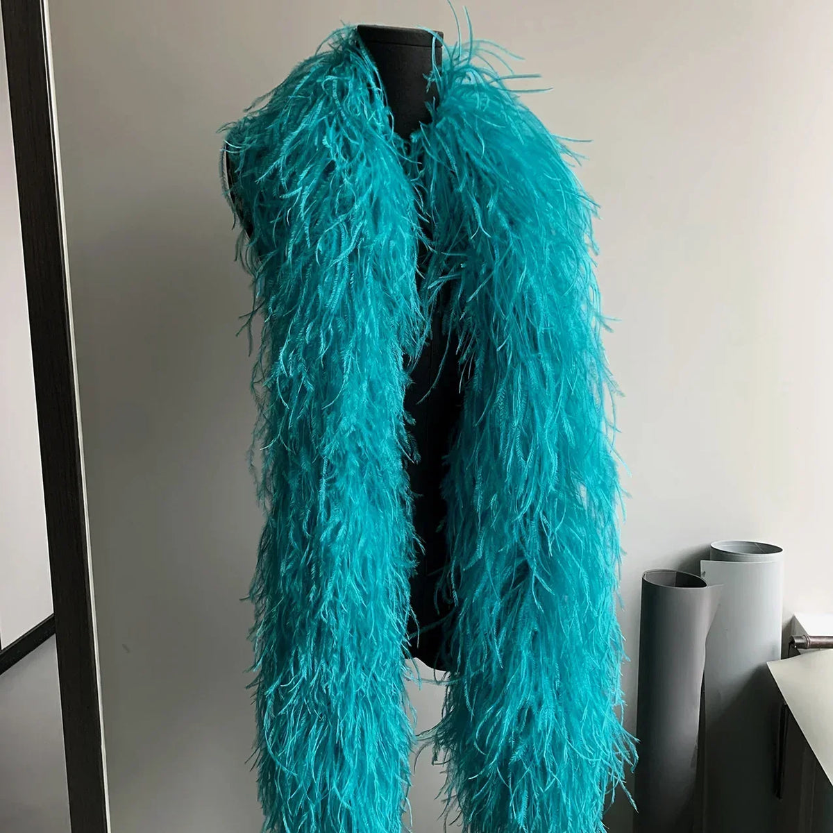 Bright turquoise ostrich feather boa displayed on a black mannequin