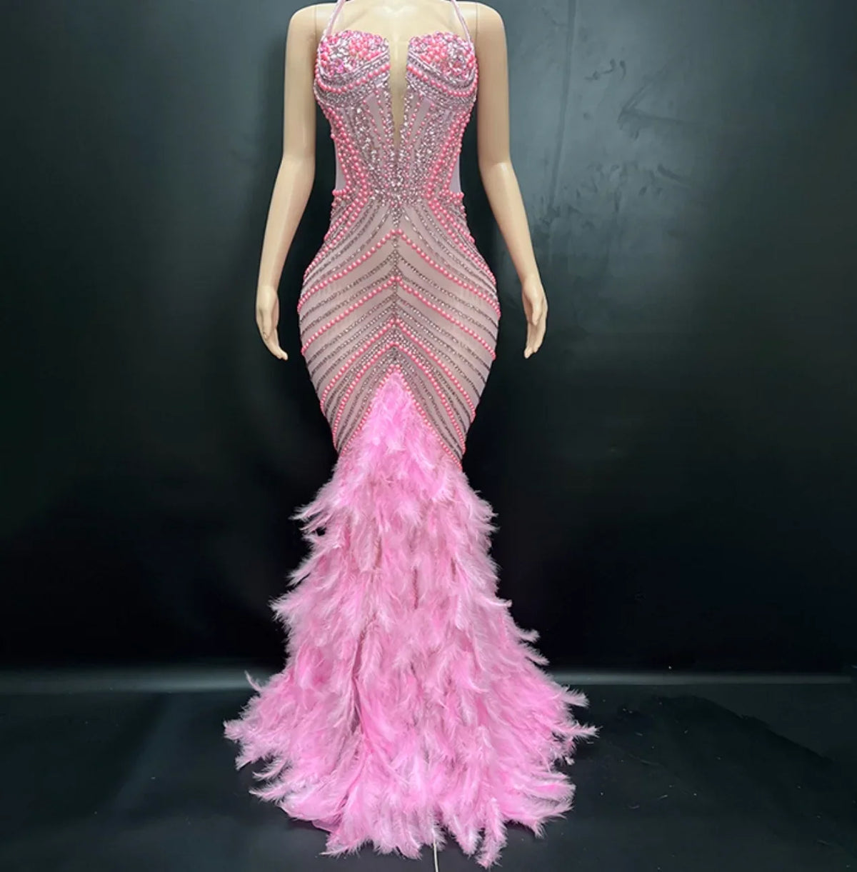 Mannequin wearing a pink and gray evening gown with feathered skirt on a black background