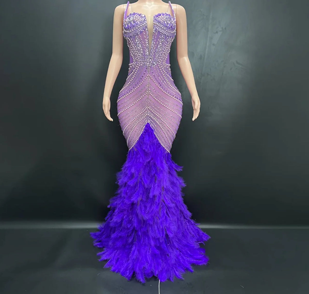 Mannequin wearing a purple evening gown with feathered skirt on a black background