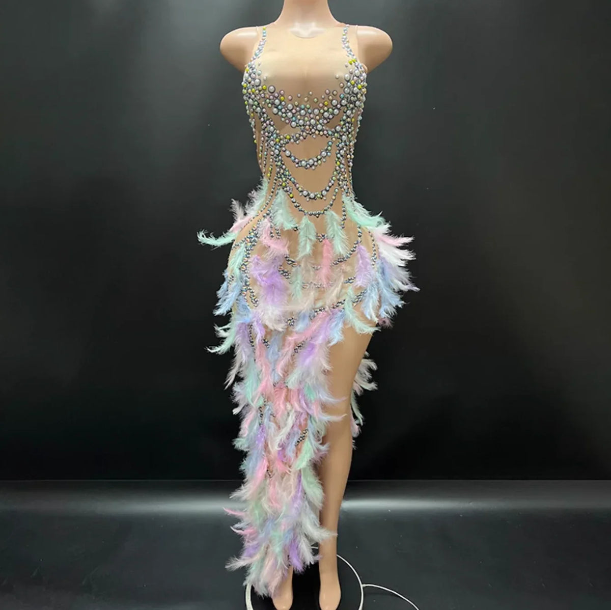 Mannequin wearing a colorful, feathered, and beaded dress against a black background