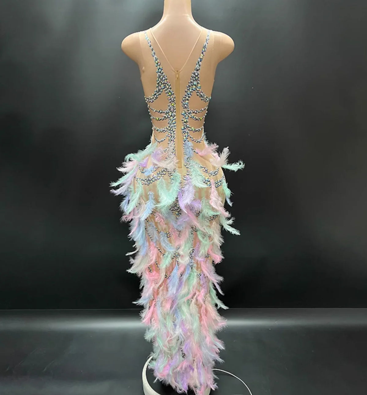 Mannequin wearing a colorful dress with feather details on a black background