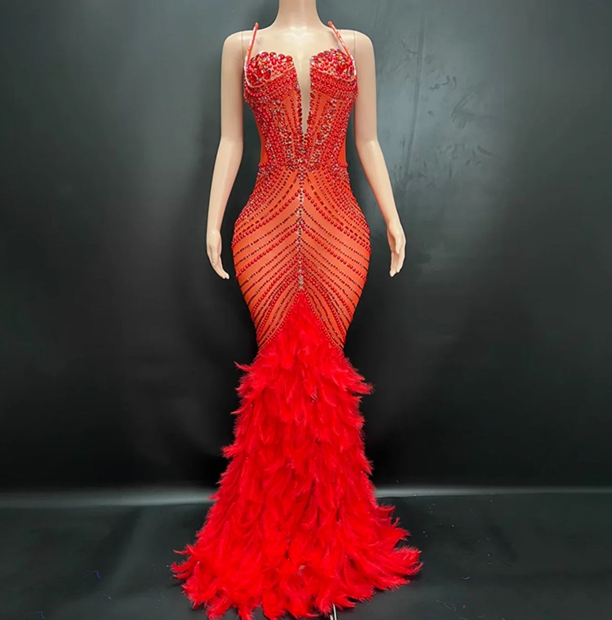 Red evening gown with feathered skirt on a mannequin against a black background