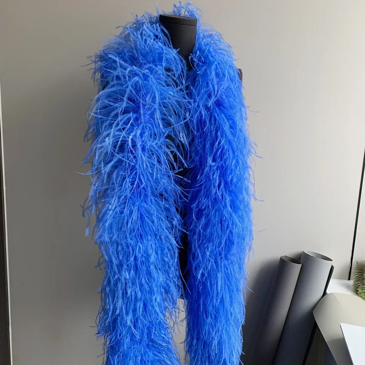 Vibrant blue ostrich feather boa draped on a black mannequin torso