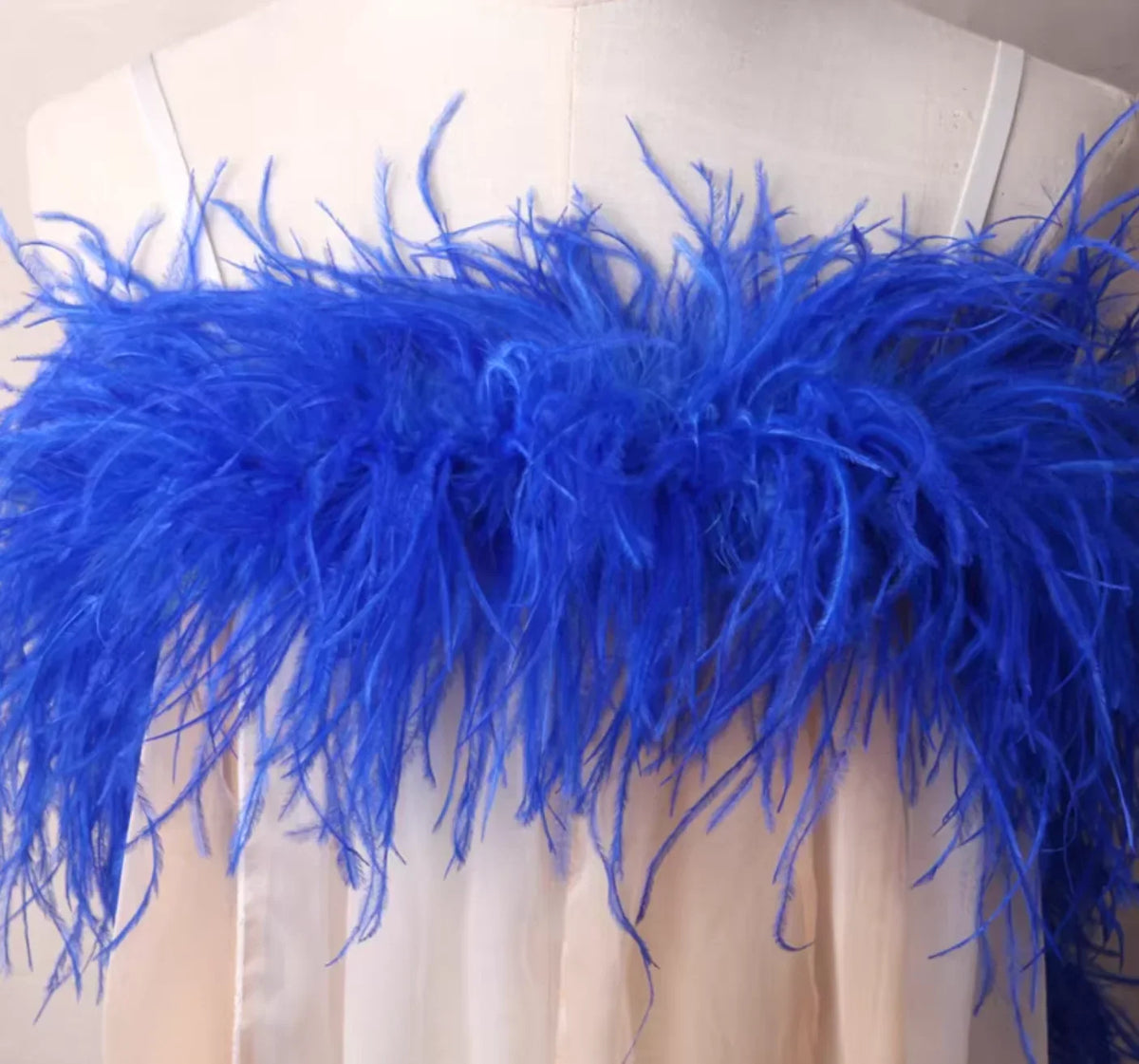 Blue feathered garment on a mannequin against a white background