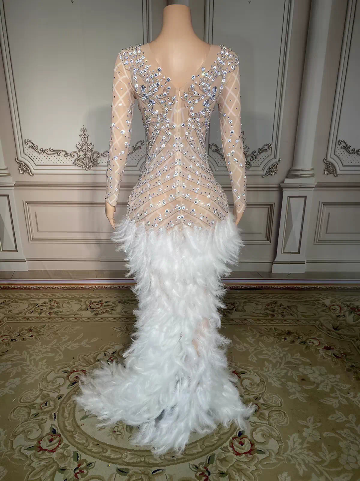 Back view of a sparkly sheer mermaid evening dress embellished with silver rhinestones and a fluffy white feather skirt.