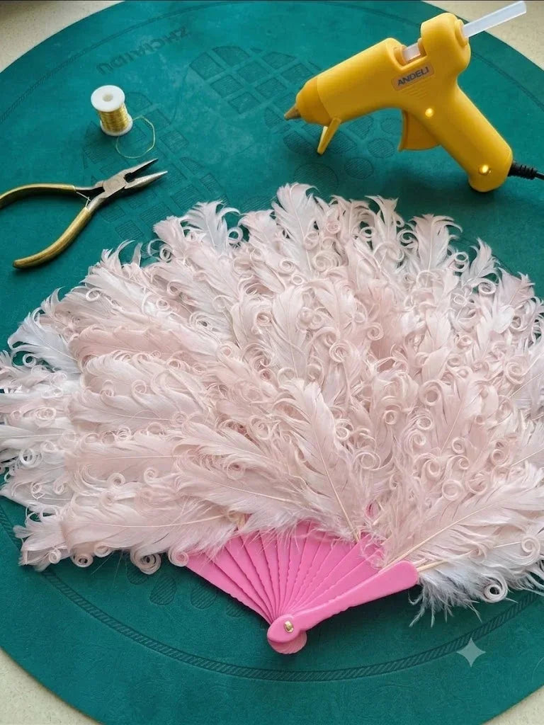 A vintage style pink ostrich feather dance fan on a dark green textured background