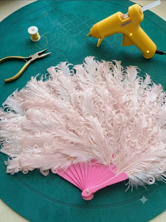 A vintage style pink ostrich feather dance fan on a dark green textured background