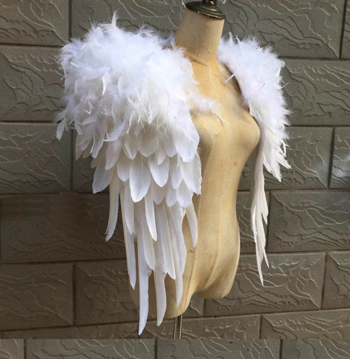 White feather angel wings worn by a mannequin, elegant costume accessory for cosplay, Halloween, and themed parties.