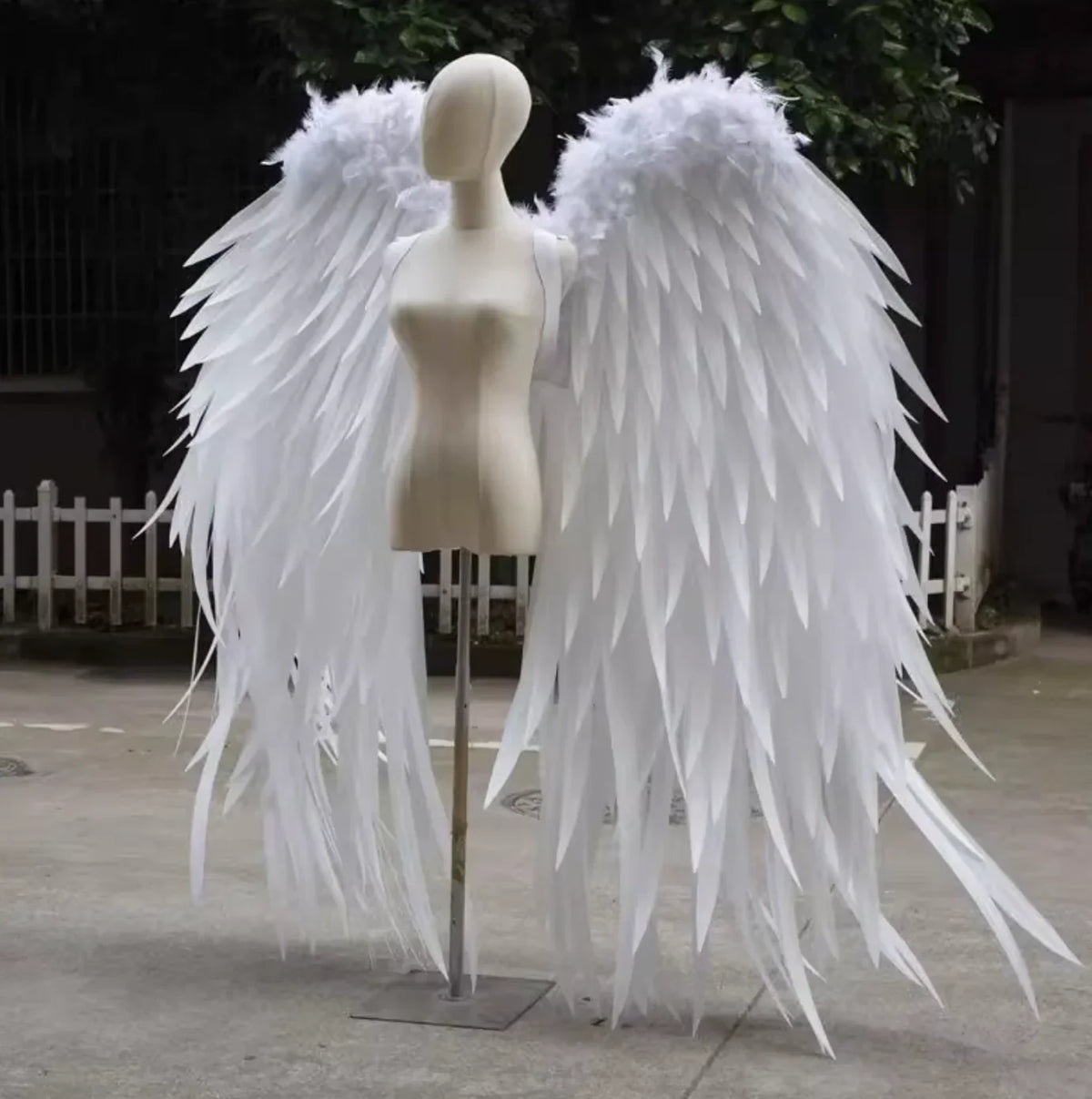 Large white feather angel wings displayed outdoors, elegant costume wings for weddings, photoshoots, and special events.