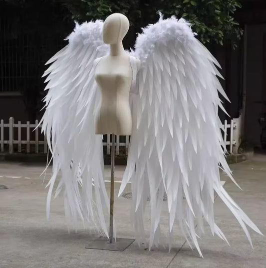 Large white feather angel wings displayed outdoors, elegant costume wings for weddings, photoshoots, and special events.