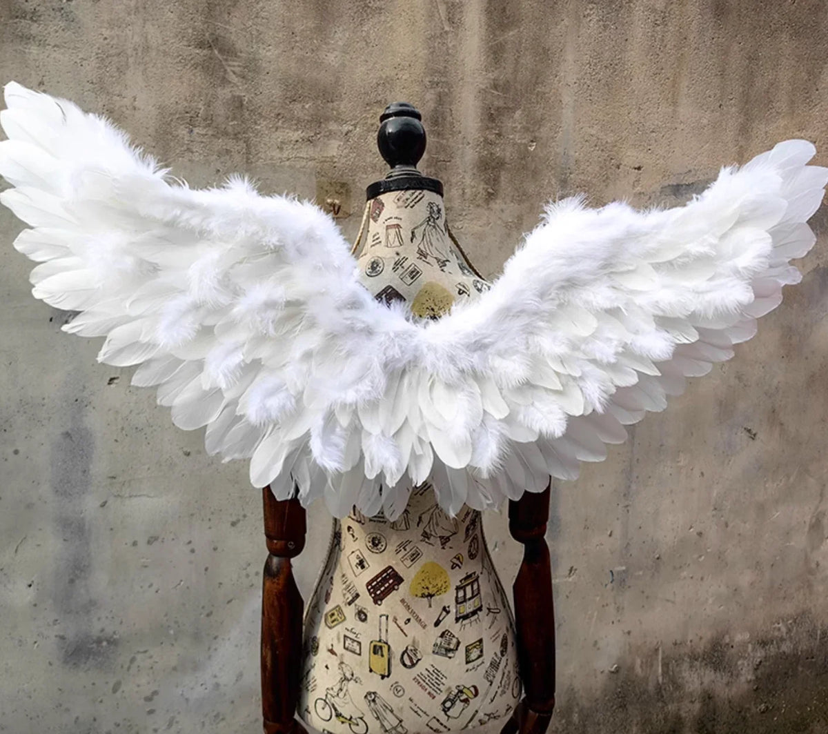White feather angel wings displayed on mannequin, realistic and fluffy for costume parties and stage use.