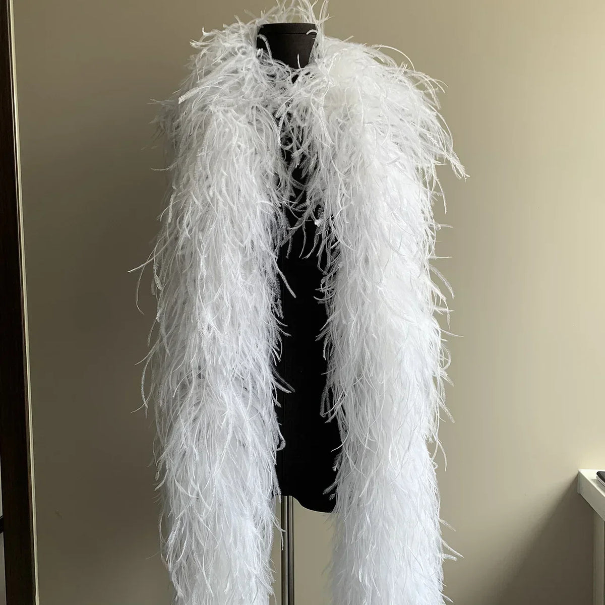 White ostrich feather boa draped on a black mannequin torso