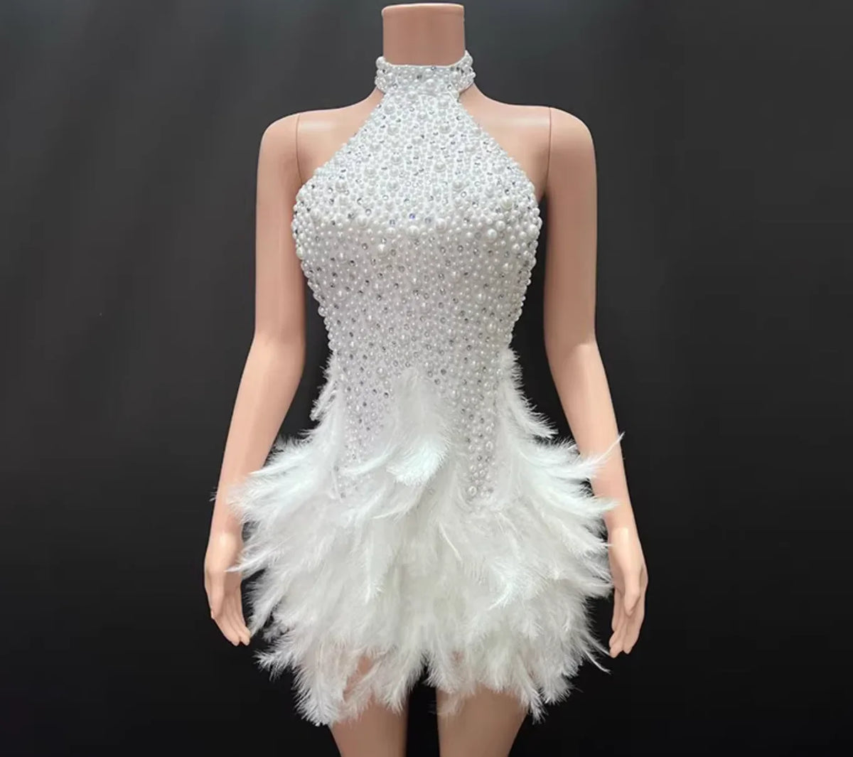 Mannequin wearing a white beaded and feathered dress against a black background