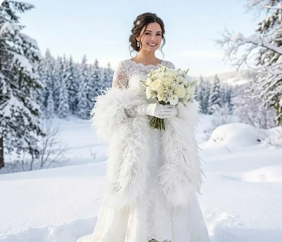 Bride in a white lace wedding dress wearing a white ostrich feather wrap in a snowy landscape